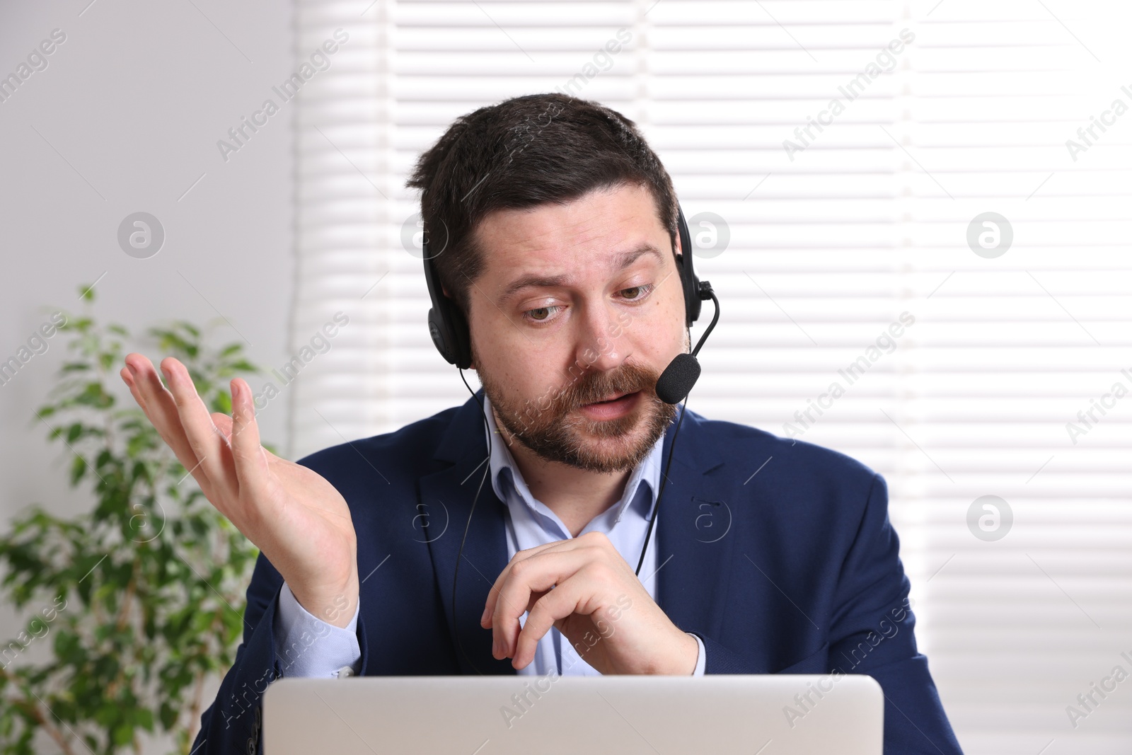 Photo of Online speaker in headset streaming webinar with laptop indoors