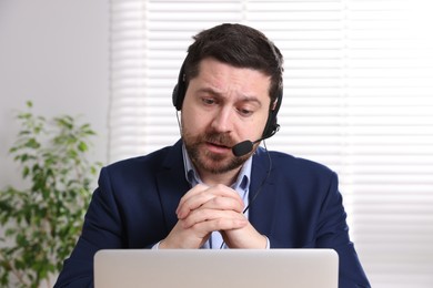 Online speaker in headset streaming webinar with laptop indoors