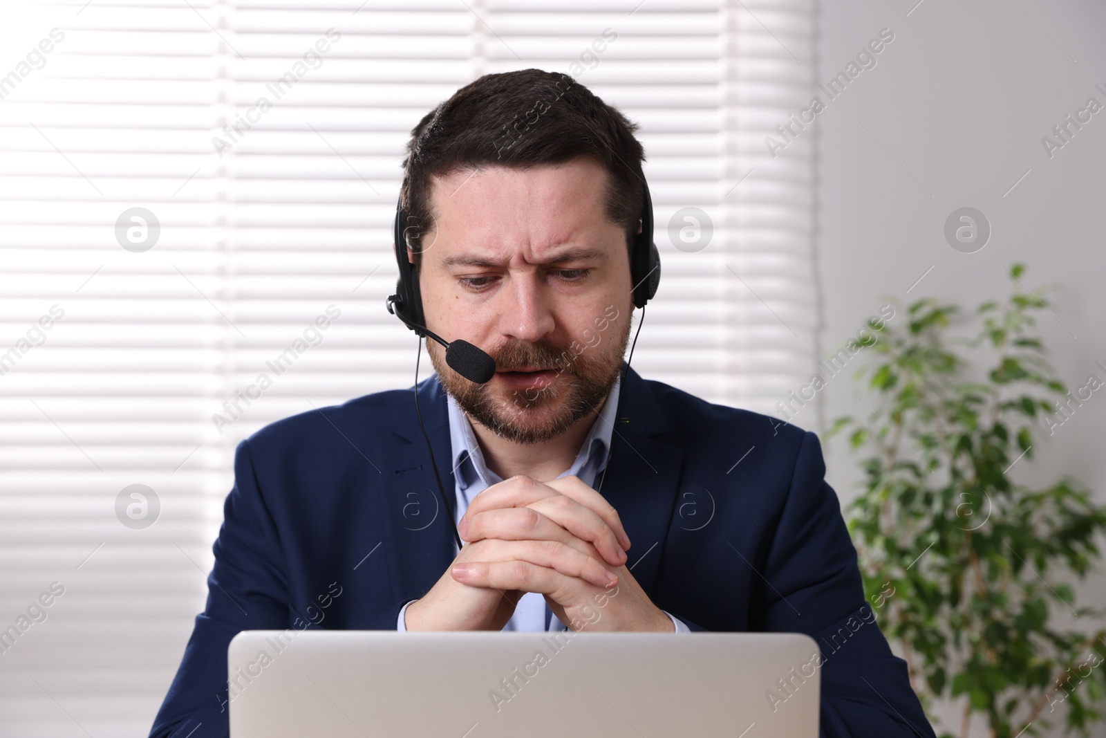 Photo of Online speaker in headset streaming webinar with laptop indoors