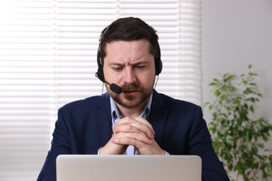 Online speaker in headset streaming webinar with laptop indoors