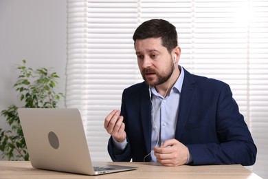 Photo of Online speaker streaming webinar with laptop at table indoors