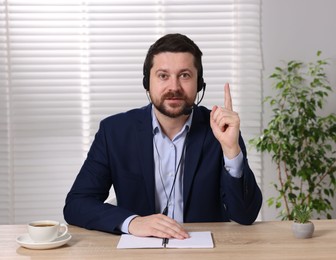 Online speaker in headset streaming webinar at table indoors, view from web camera