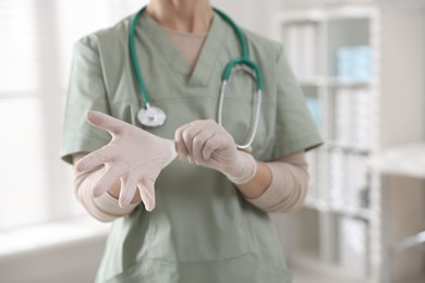 Photo of Medical worker putting gloves in hospital, closeup