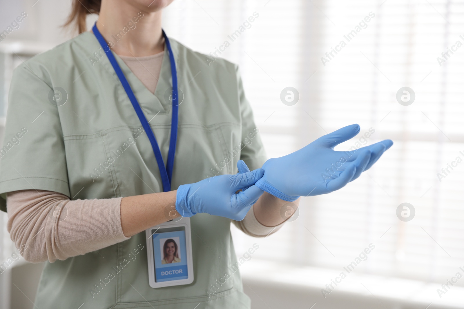 Photo of Medical worker putting gloves in hospital, closeup