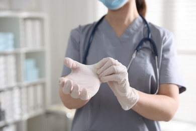 Photo of Medical worker putting gloves in hospital, closeup