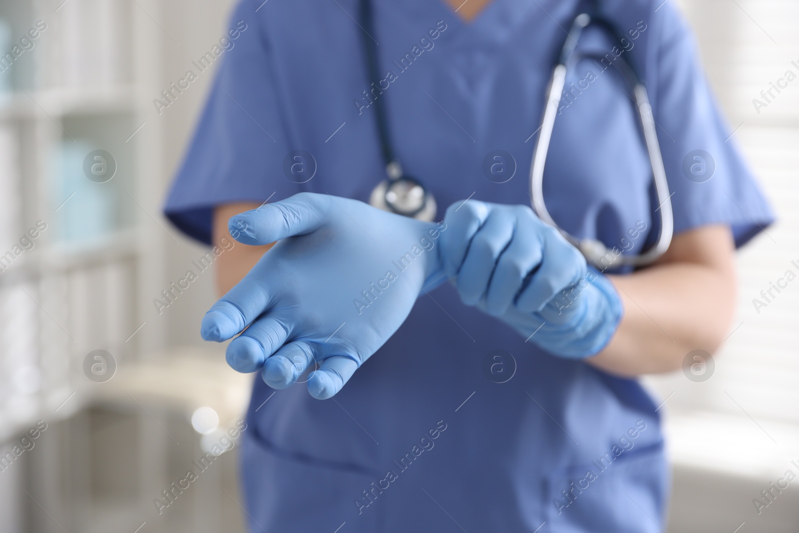 Photo of Medical worker putting gloves in hospital, closeup