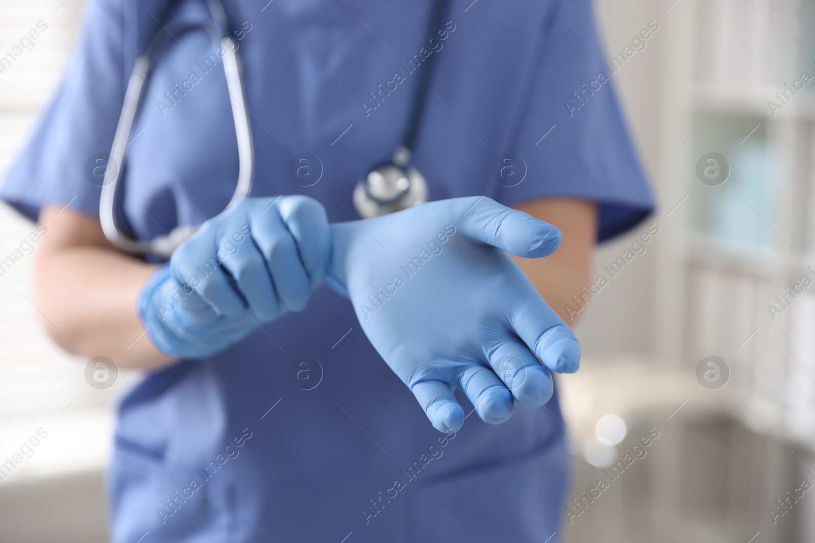 Photo of Medical worker putting gloves in hospital, closeup