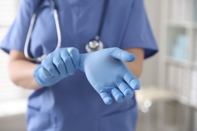 Medical worker putting gloves in hospital, closeup