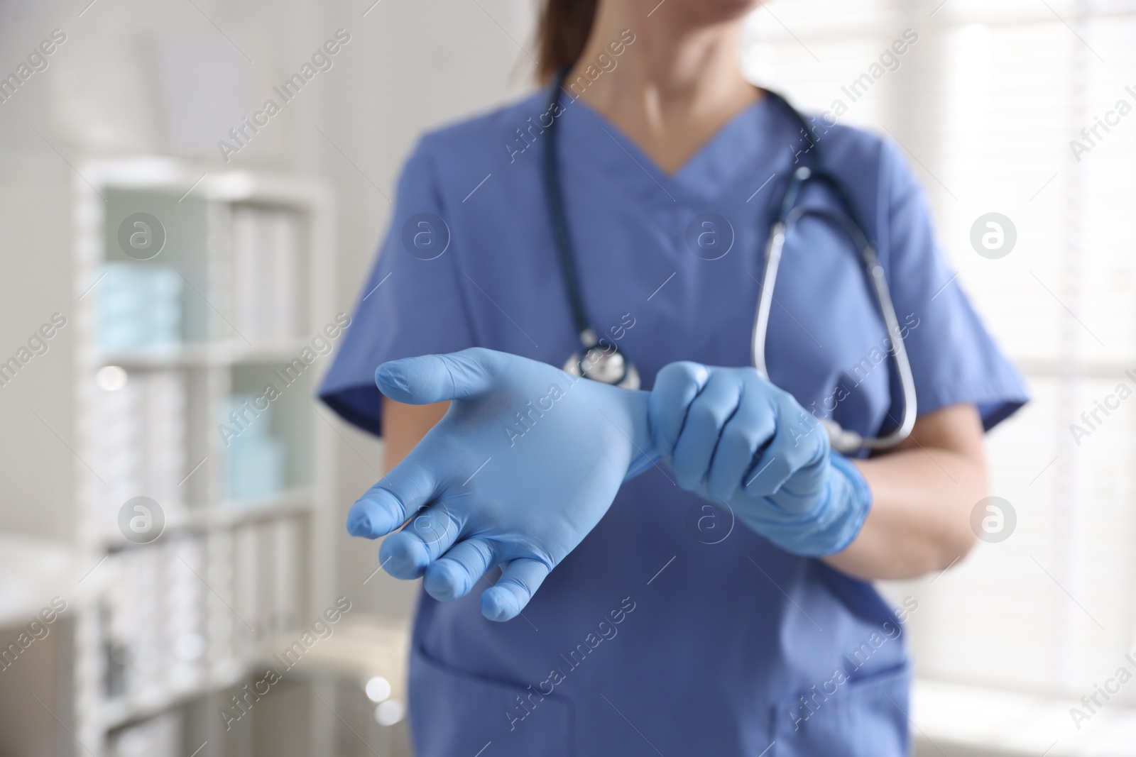 Photo of Medical worker putting gloves in hospital, closeup