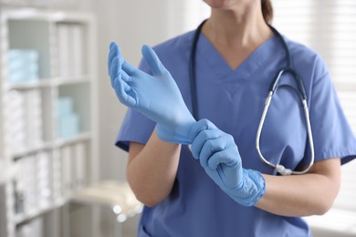 Photo of Medical worker putting gloves in hospital, closeup