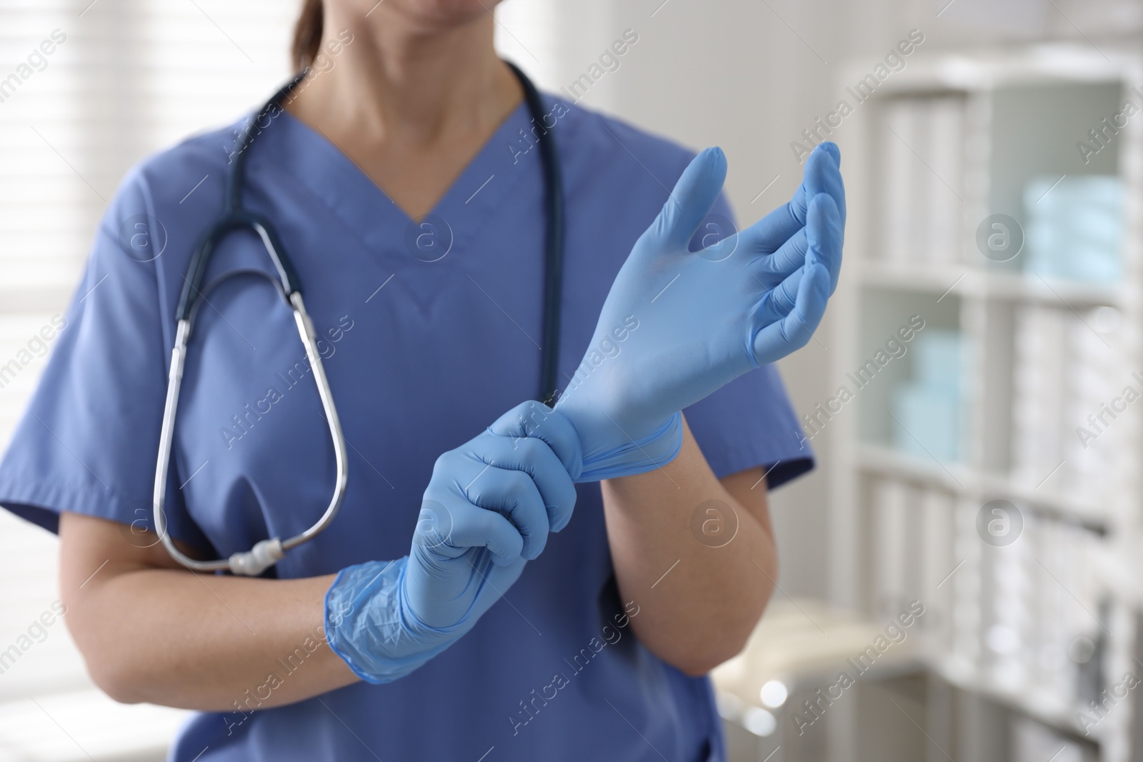 Photo of Medical worker putting gloves in hospital, closeup