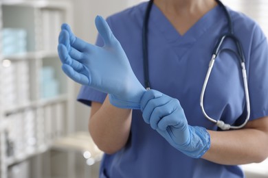 Photo of Medical worker putting gloves in hospital, closeup