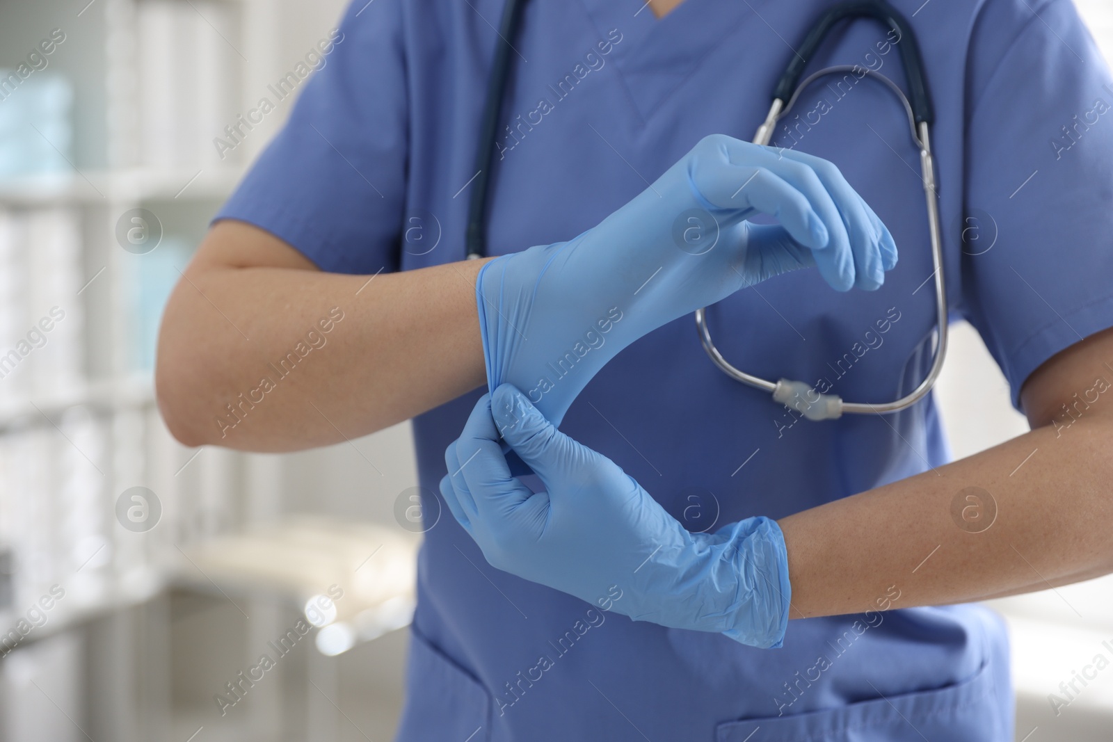 Photo of Medical worker putting gloves in hospital, closeup