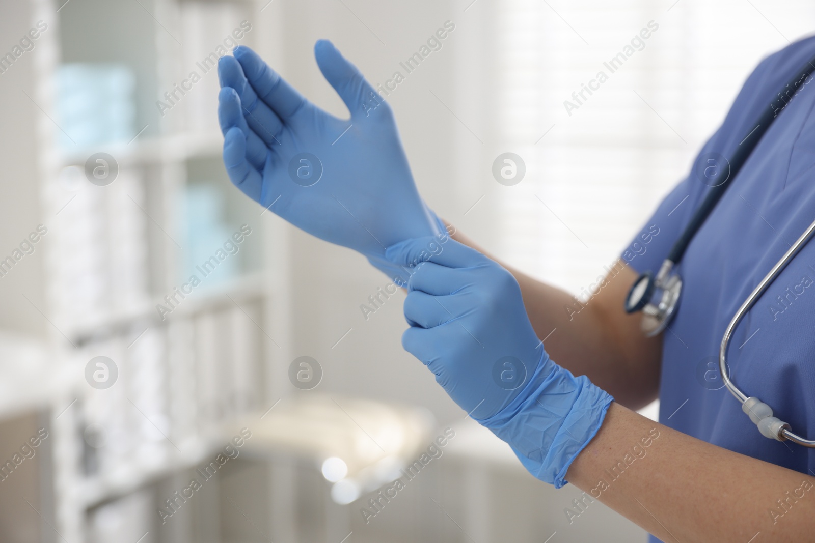 Photo of Medical worker putting gloves in hospital, closeup