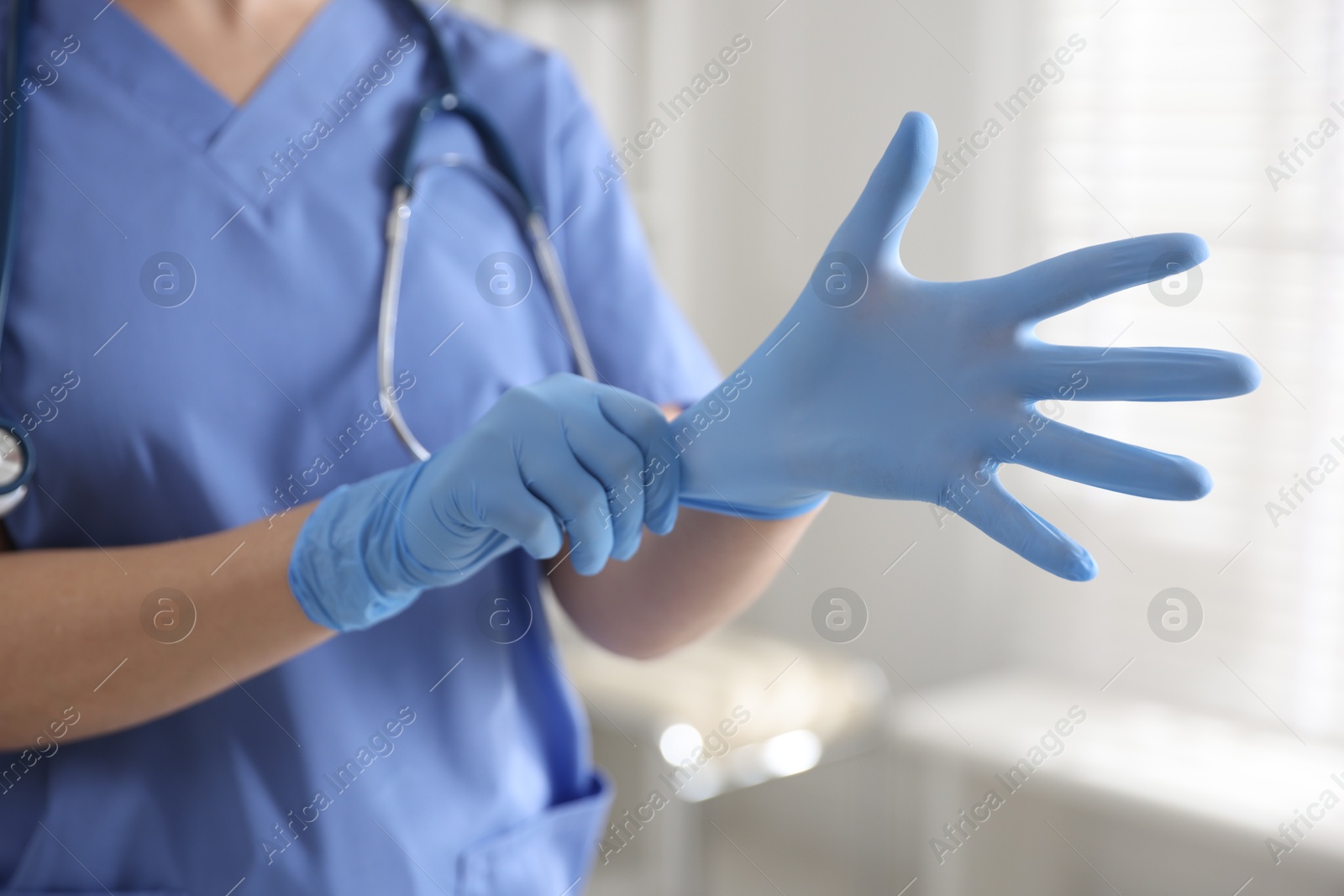 Photo of Medical worker putting gloves in hospital, closeup