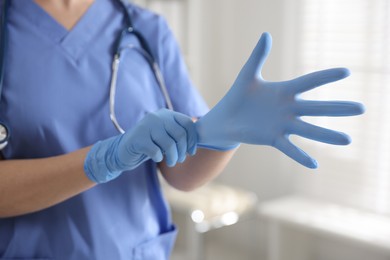 Photo of Medical worker putting gloves in hospital, closeup