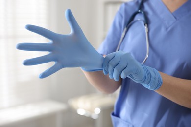 Medical worker putting gloves in hospital, closeup