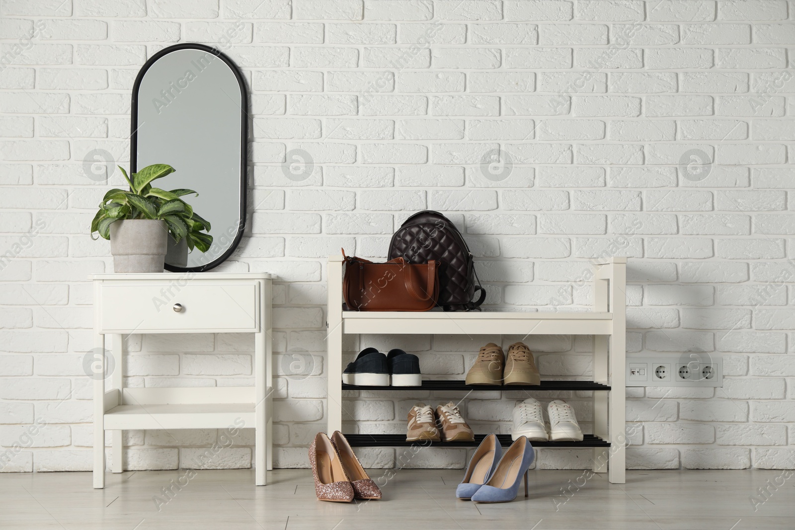 Shoe storage bench with different footwear and houseplant indoors Photo of Shoe storage bench with different footwear and houseplant indoors