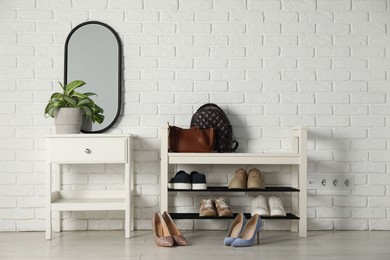 Photo of Shoe storage bench with different footwear and houseplant indoors