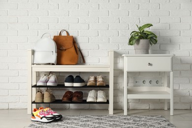 Photo of Shoe storage bench with different footwear and houseplant indoors