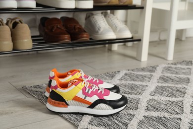Photo of Shoe storage bench with different footwear indoors, focus on sneakers