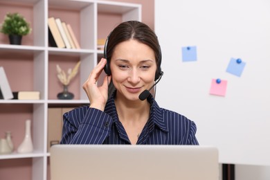 Online speaker in headset streaming webinar with laptop indoors