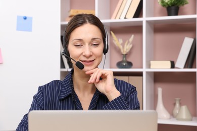 Online speaker in headset streaming webinar with laptop indoors