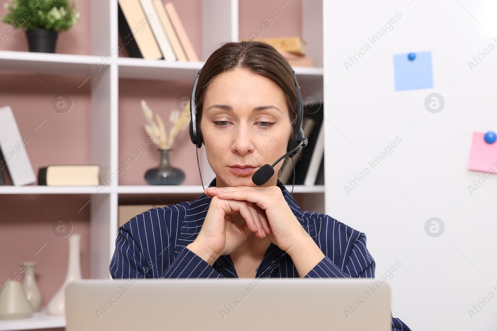 Photo of Online speaker in headset streaming webinar with laptop indoors