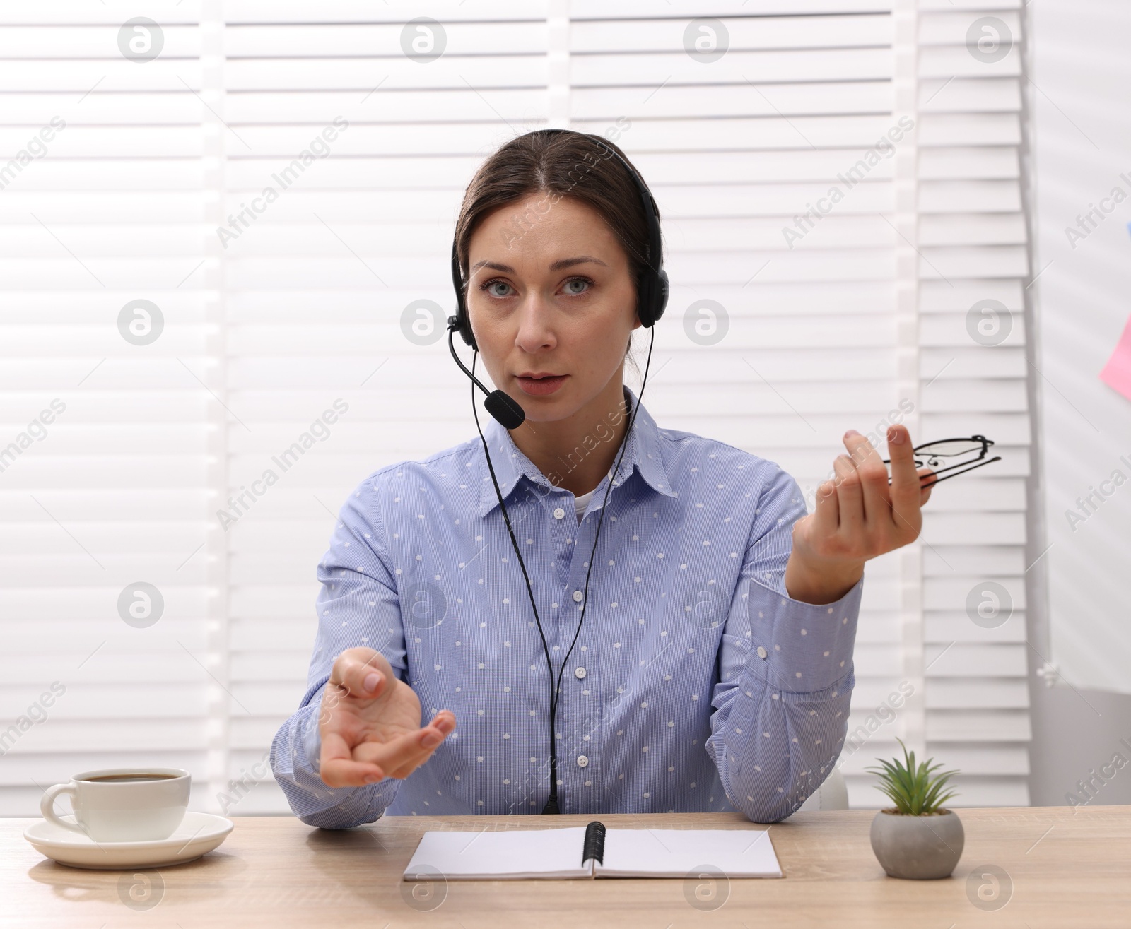 Photo of Online speaker in headset streaming webinar at table indoors, view from web camera