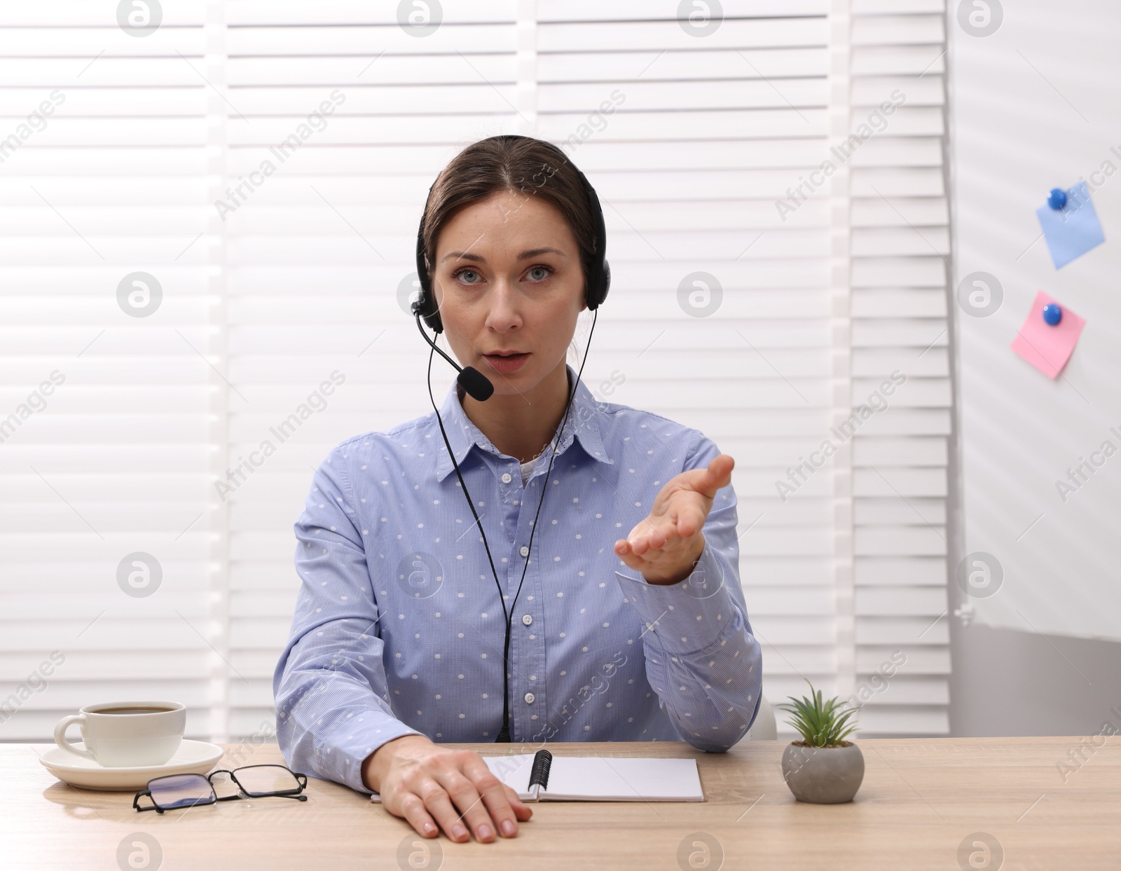 Photo of Online speaker in headset streaming webinar at table indoors, view from web camera