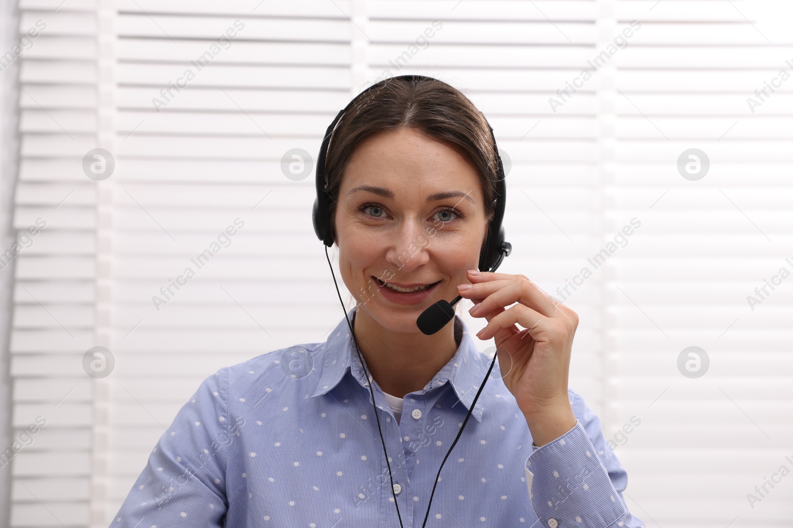 Photo of Smiling online speaker in headset streaming webinar indoors, view from web camera