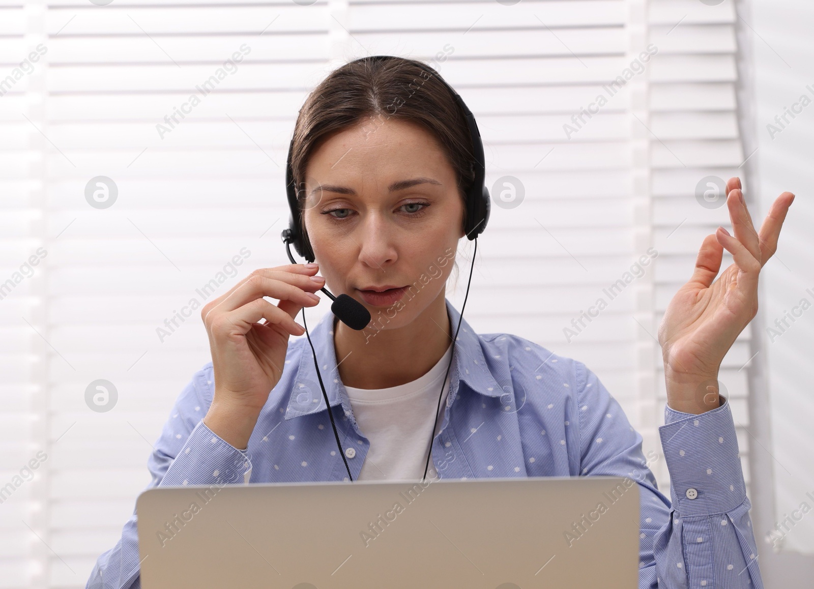 Photo of Online speaker in headset streaming webinar with laptop indoors