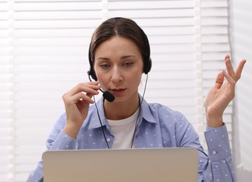 Online speaker in headset streaming webinar with laptop indoors