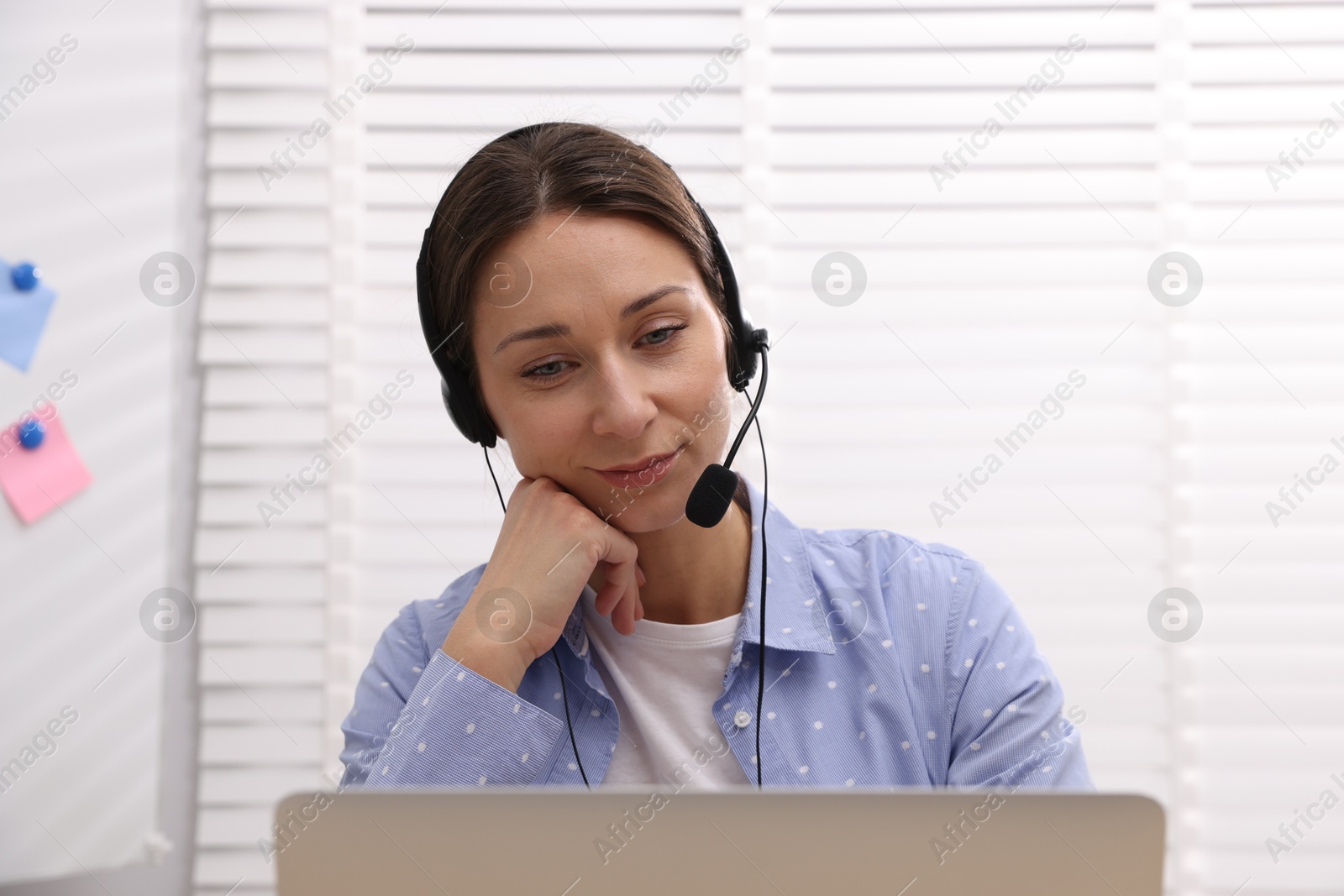 Photo of Online speaker in headset streaming webinar with laptop indoors