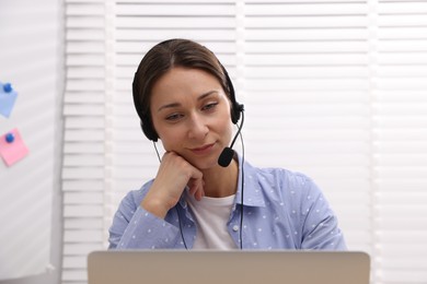 Online speaker in headset streaming webinar with laptop indoors