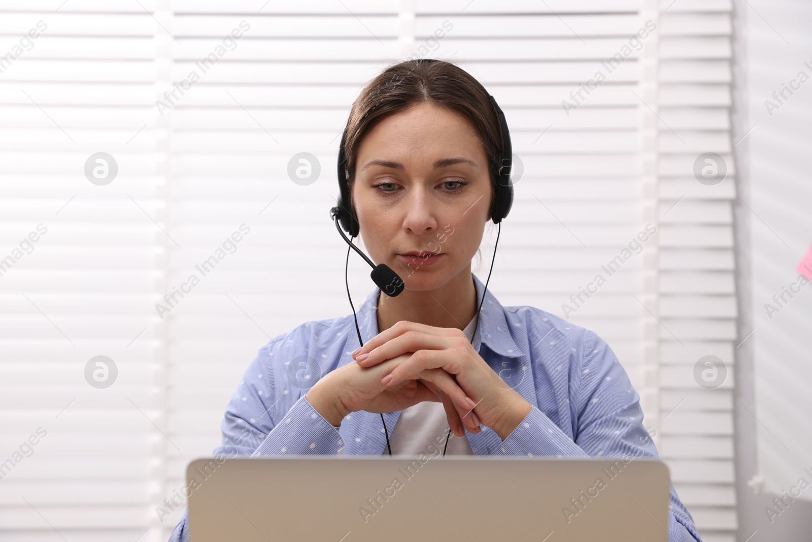 Photo of Online speaker in headset streaming webinar with laptop indoors