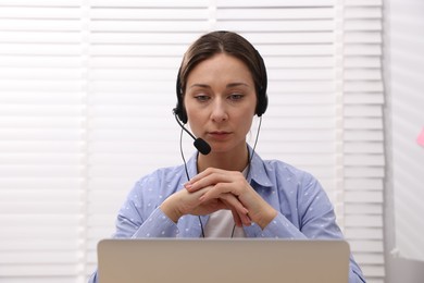 Online speaker in headset streaming webinar with laptop indoors