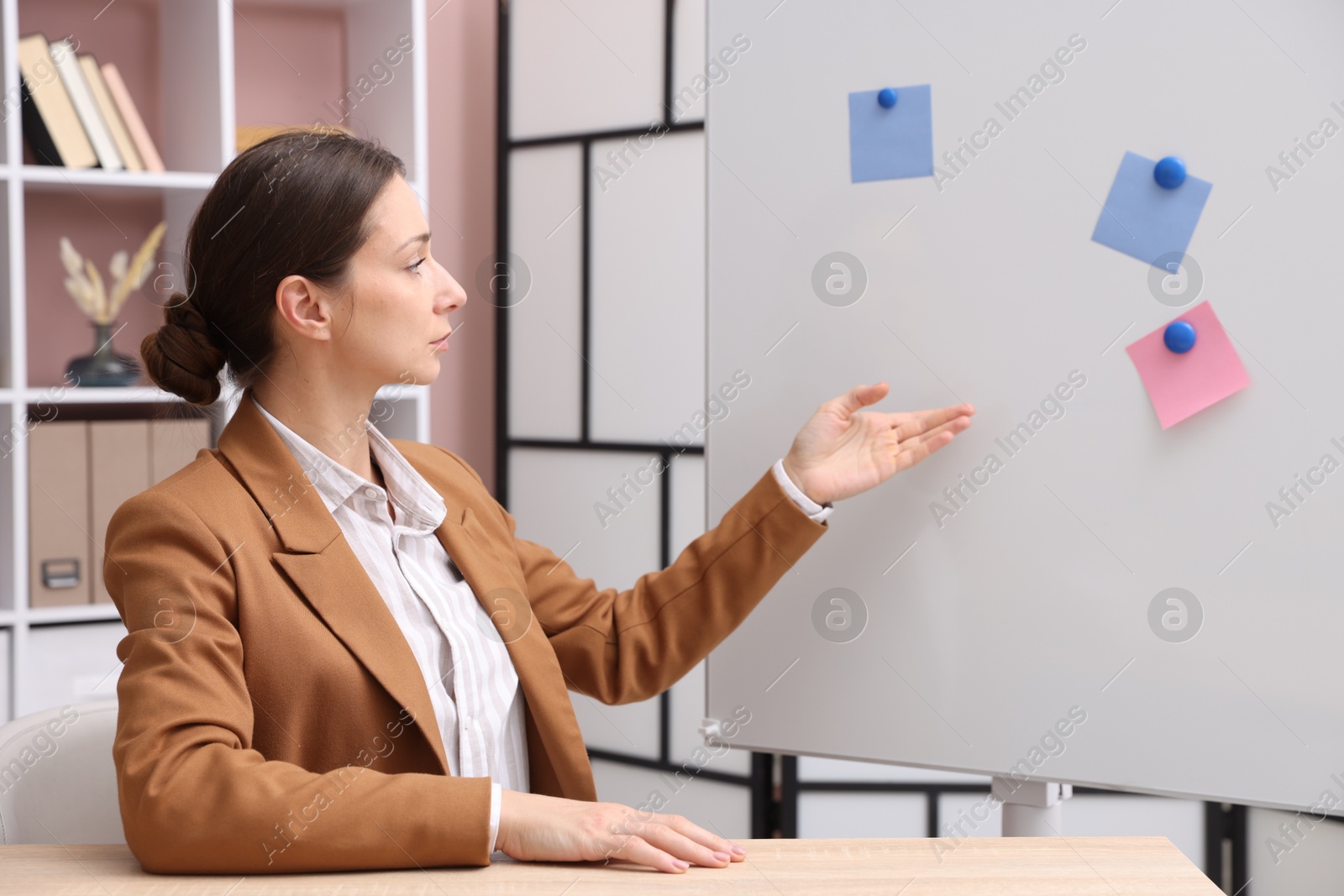 Photo of Online speaker performing webinar near flip chart indoors