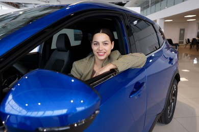 Happy woman inside new car in salon