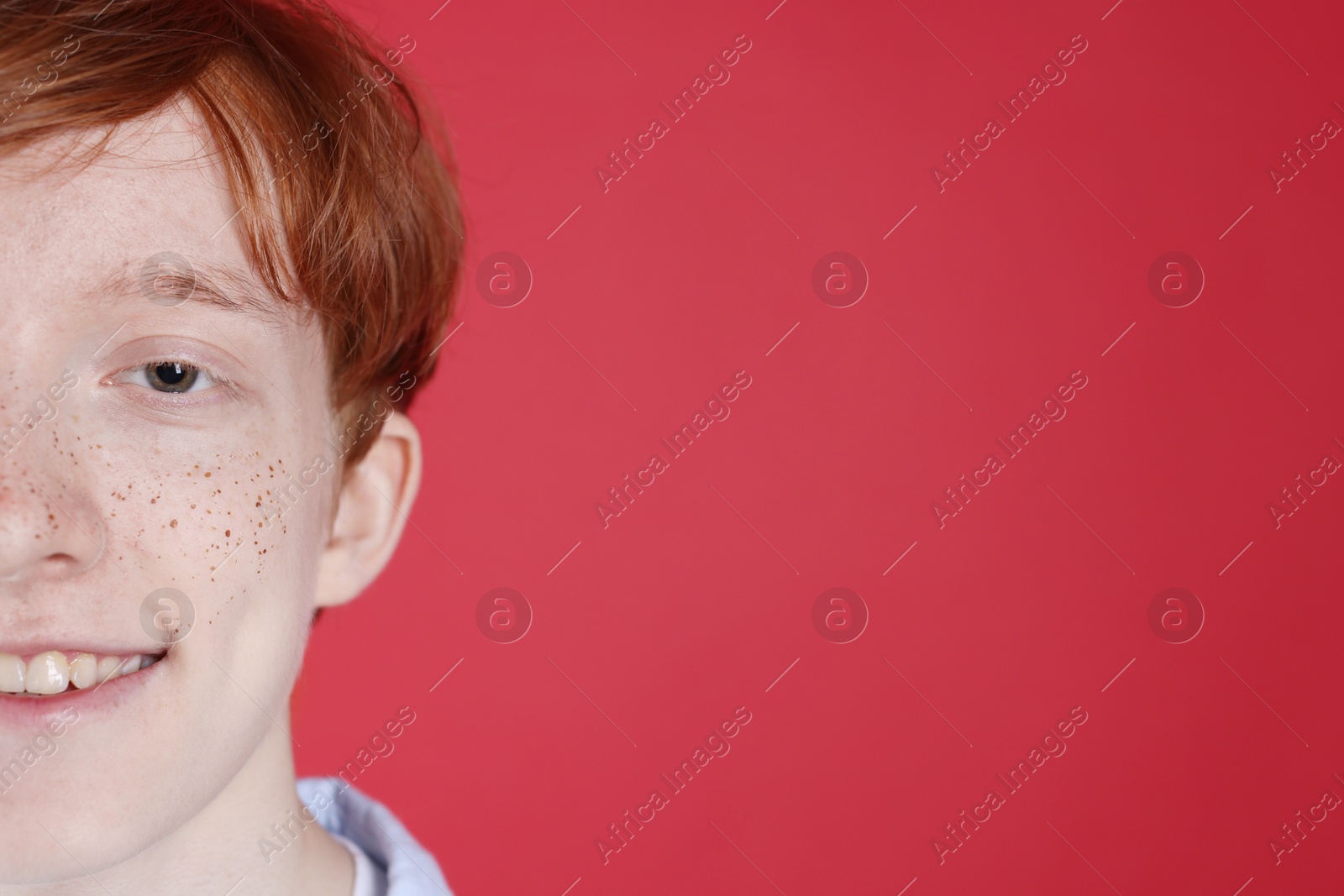 Smiling teenage boy with freckles on red background, closeup. Space for text Photo of Smiling teenage boy with freckles on red background, closeup. Space for text