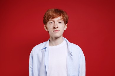 Photo of Cute teenage boy with freckles on dark red background