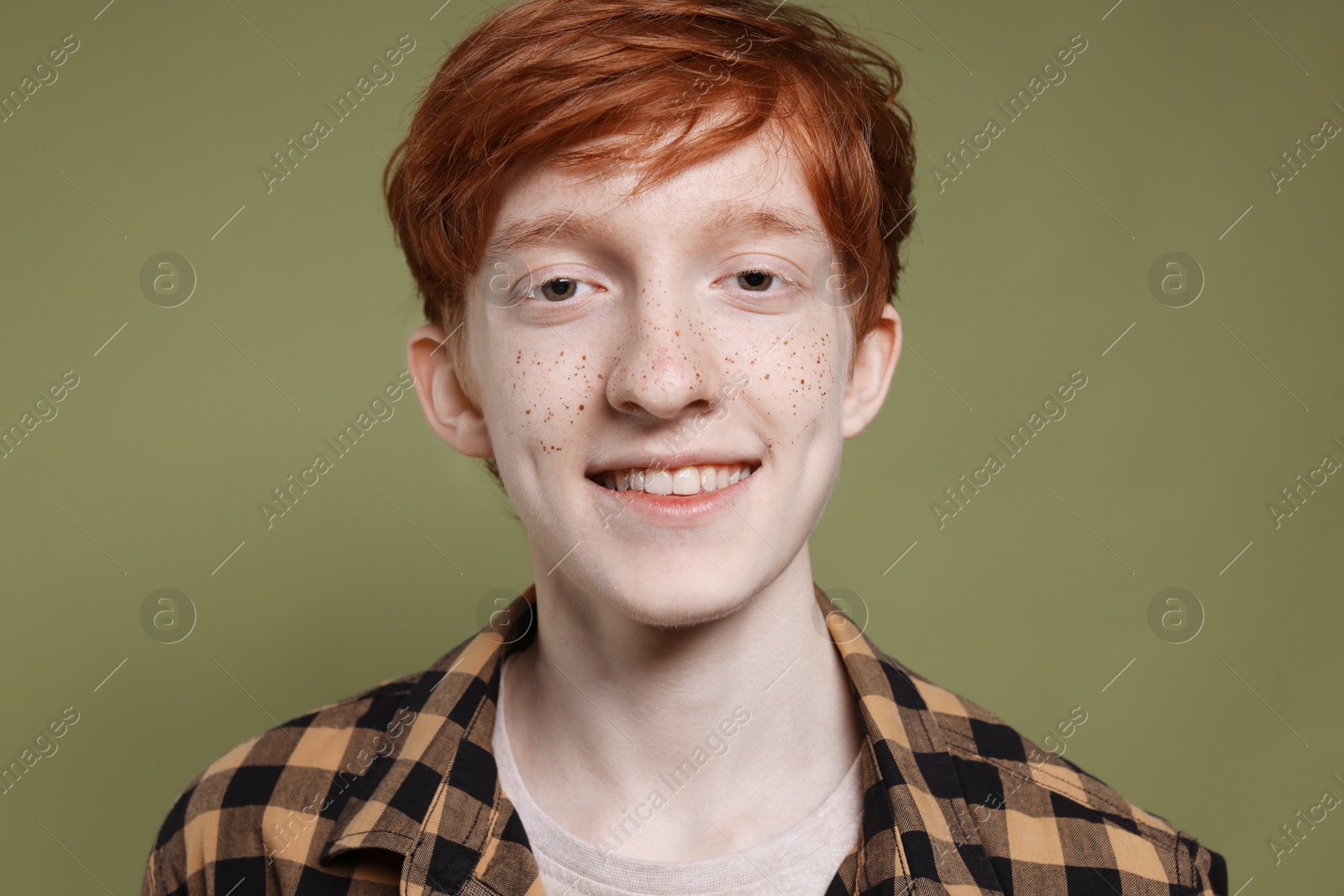 Photo of Smiling teenage boy with freckles on dark green background