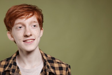 Photo of Smiling teenage boy with freckles on dark green background. Space for text