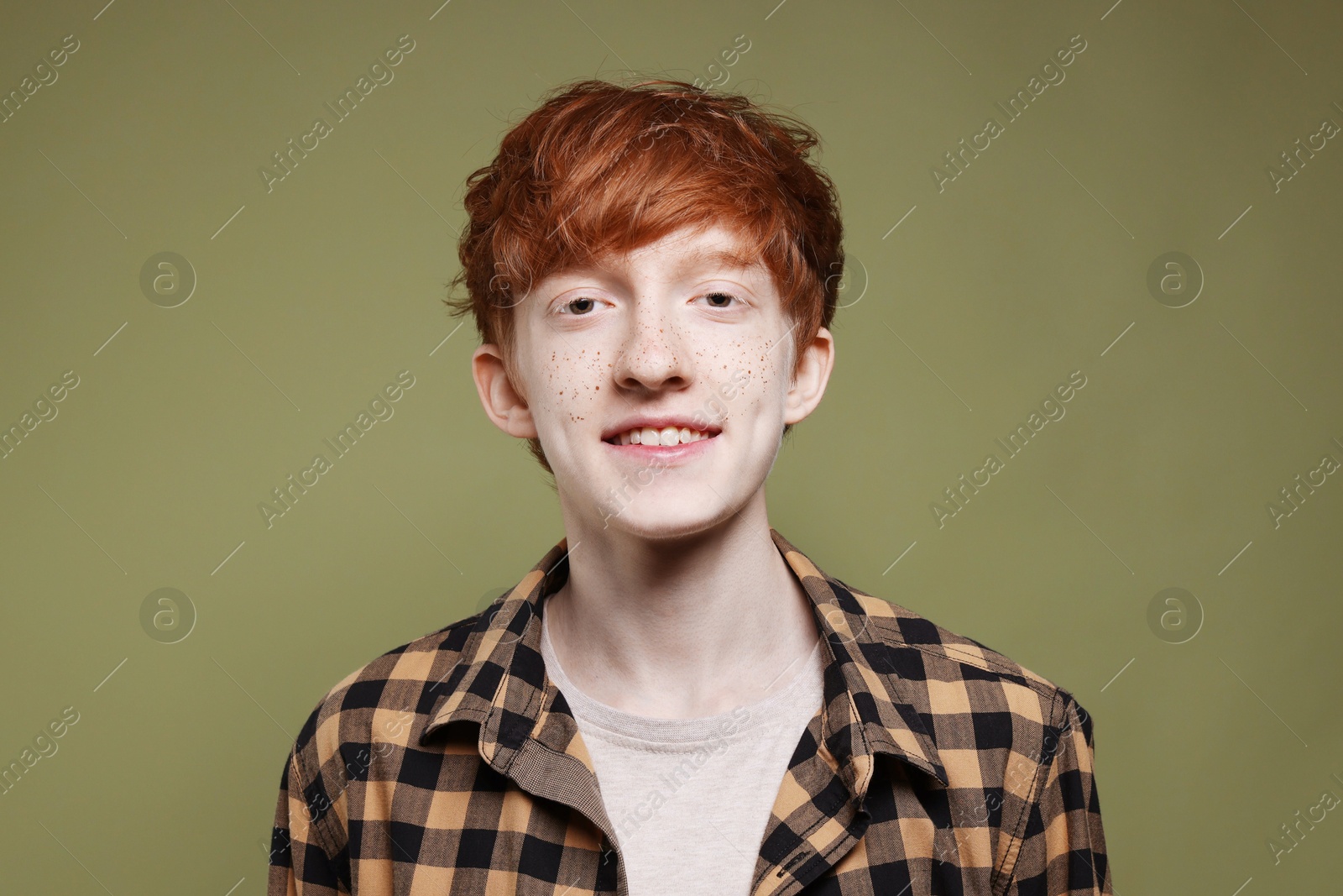 Photo of Portrait of smiling teenage boy with freckles on dark green background