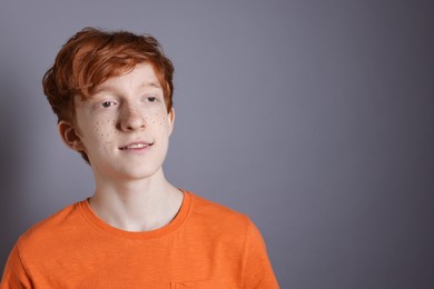 Photo of Smiling teenage boy with freckles on grey background. Space for text