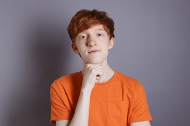 Photo of Portrait of cute teenage boy with freckles on grey background