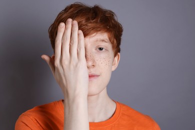 Photo of Cute teenage boy with freckles on grey background