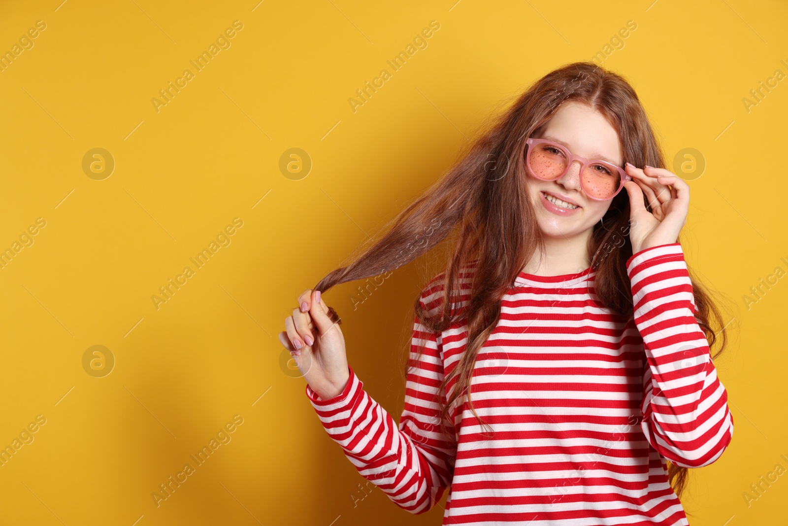 Photo of Beautiful freckled teenage girl with sunglasses on orange background, space for text