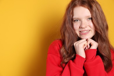 Beautiful teenage girl with freckles on orange background, space for text