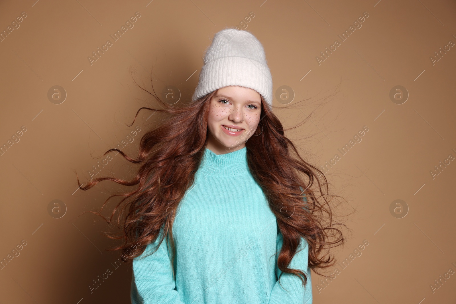 Photo of Beautiful teenage girl with freckles in hat on brown background